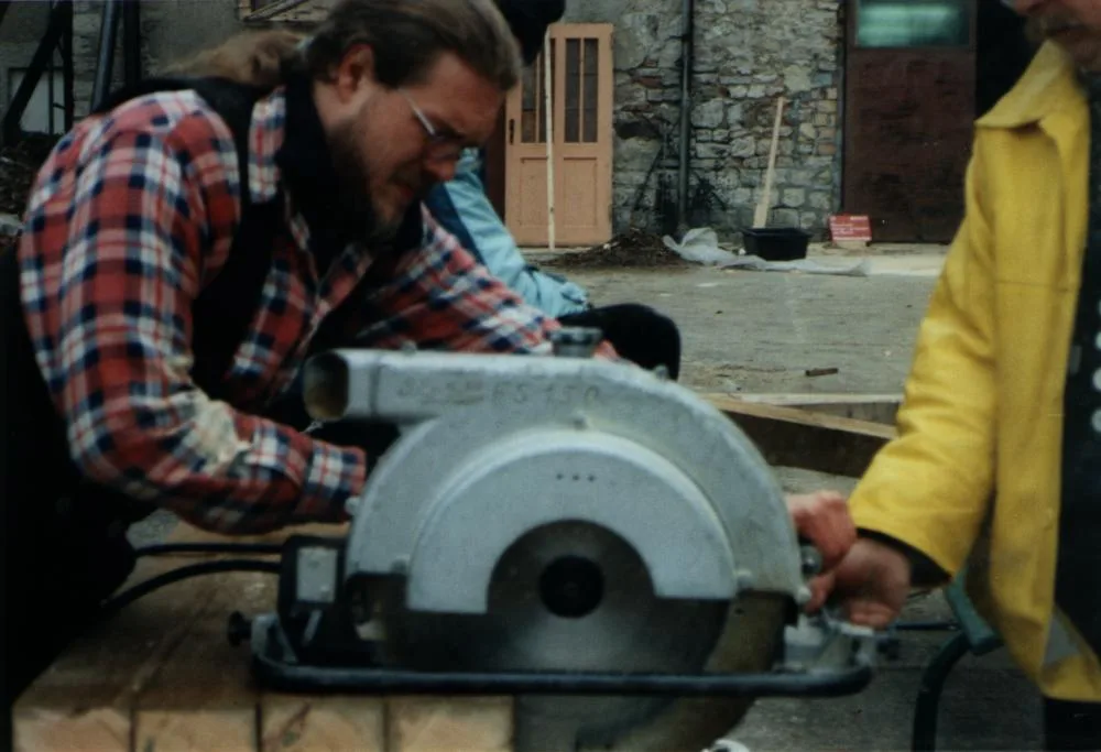 A person using a handheld circular saw on a wooden workpiece.