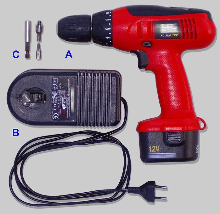 A cordless drill, battery charger and screwdriver bits laid out together.